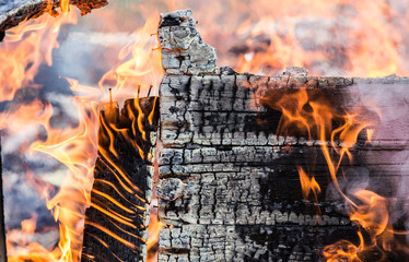 Detail view of burning painted wooden board wall fallen apart, lot of smoke, flames and charcoal. Home house fire concept.  © FotoHelin