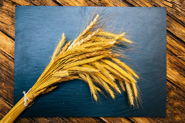 Ear of wheat or spike on the black background wooden table. Bakery or bread concept image.