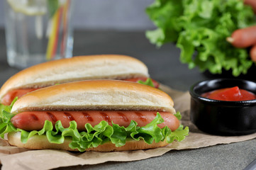 Two hot dogs on craft paper. The concept of a quick and tasty snack. Dark background. close-up.