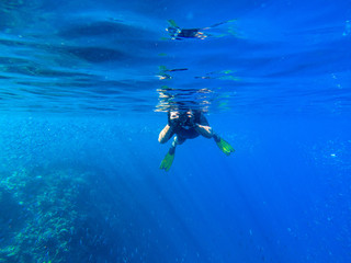 Obraz na płótnie Canvas Man with underwater photocamera in blue sea water. Snorkeling in tropical seaside. Summer vacation in exotic island