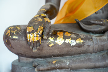 Selective focus on closeup hand of buddha statue coated by the golden leaf
