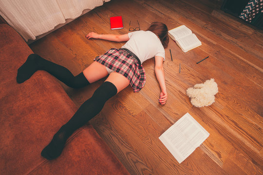 Tired Sexy School Girl Sleeping On The Floor. Young Woman In Sexy School Skirt On The Floor. College Girl Joke Concept. Preparing Exams