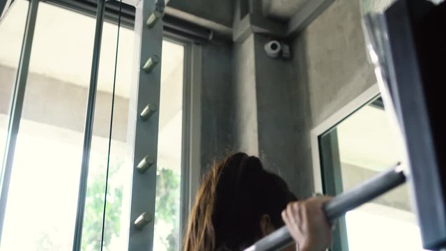 Young woman doing barbell squat exercise on machine at the gym