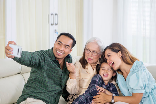 Cheerful three generation family takes selfie at home