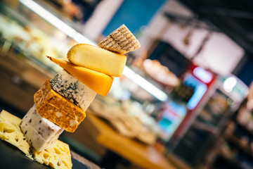 Assorted, various aged cheeses on plate or board. Different kind or type of delicious cheese on cheese platter. 