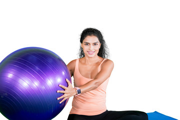 Curly hair woman holding a yoga ball on studio