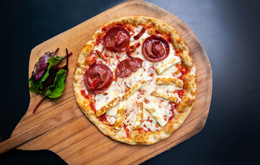 Delicious, fresh and tasty flat bread italian pepperoni or margherita pizza. View of Salami, cheese and basil pizza in restaurant at napoli. Pizza on wooden pizza shovel board.