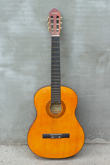 Obraz premium Wooden six-string guitar. Close-up of a guitar lying on a concrete background