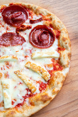 Delicious, fresh and tasty flat bread italian pepperoni or margherita pizza. View of Salami, cheese and basil pizza in restaurant at napoli. Pizza on wooden pizza shovel board.