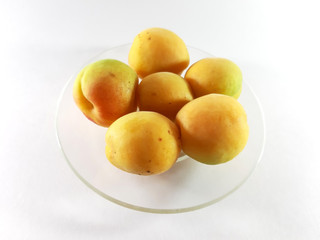 Whole apricots on a plate. Isolated photo. Yellow ripe round apricots