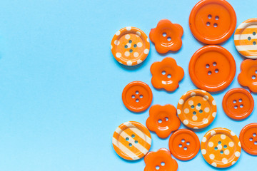 Fototapeta premium Various orange sewing buttons on blue background