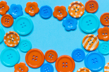 Various orange and blue sewing buttons on blue background