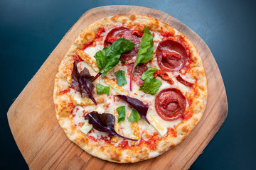 Delicious, fresh and tasty flat bread italian pepperoni or margherita pizza. View of Salami, cheese and basil pizza in restaurant at napoli. Pizza on wooden pizza shovel board.