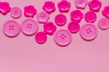 Fototapeta na wymiar Various pink sewing buttons on light pink background
