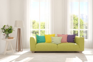 Stylish room in white color with sofa and summer landscape in window. Scandinavian interior design. 3D illustration