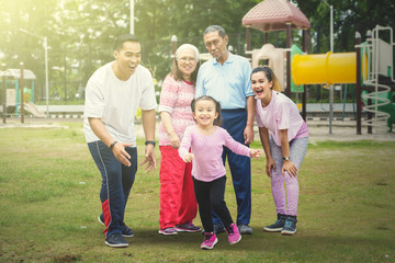 Happy little girl plays with her family in the park