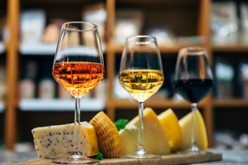 Glasses of Wine and cheese. Assortment or various type of cheese and wine glasses on the table in restaurant. Red, rose and yellow wine or champagne on the table. Winery concept image