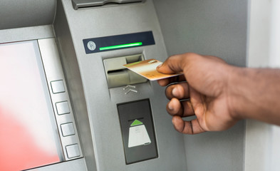 Close up of man using ATM with gold credit card