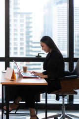 Shot of a beautiful young businesswoman using laptop and doing some paperwork while working on laptop