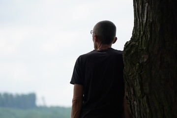 Silhouette eines Mannes von hinten an einem Baum