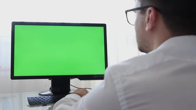 LOS ANGELES, CALIFORNIA - JUNE 3, 2019: Engineer, Constructor, Designer in Glasses Working on a Personal Computer with a Green Screen on Monitor which has Chroma Key Great for Mockup Template