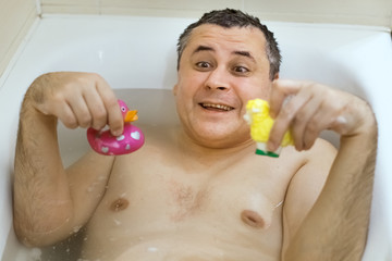 Funny comic adult man fooling in the bathroom, he plays with children's toys.