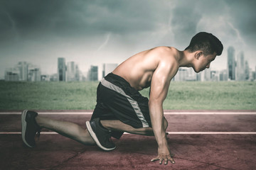 Fototapeta premium Muscular young man kneeling on the track