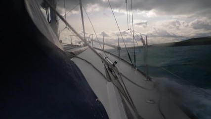 View down the starboard rail of a sailing boat pounding into the swells inshore