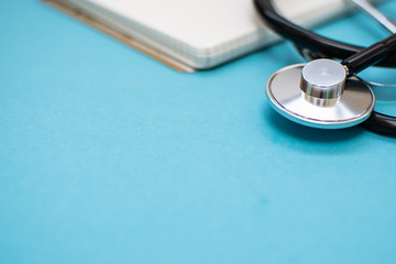 Stethoscope and blank notebook on the blue table close up. Copy space for your text. Health care...