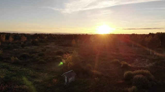 Wonderful sunset in autumn evening, beauty of nature, lens flare natural effect. Wooden hut in the middle of the meadow