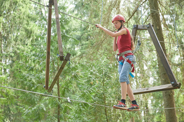 Naklejka na ściany i meble Girl at climbing activity in high wire forest park