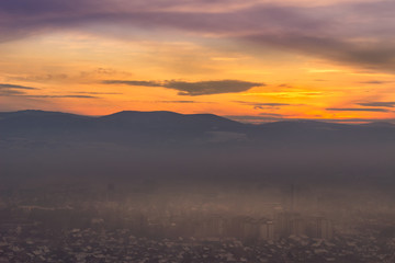 Beautiful view of misty Pirot cityscape covered by first winter snow and stunning blue hour colors in the sky