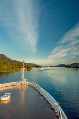 Pointed bow of cruise ship , southbound on ocean channel, Alaska Inside Passage, in warm afternoon sun.