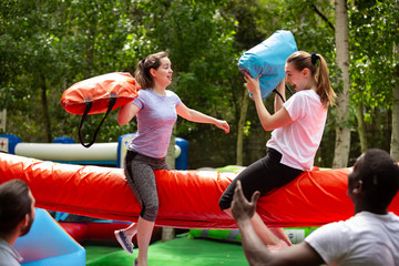Women fighting by pillows on inflatable beam