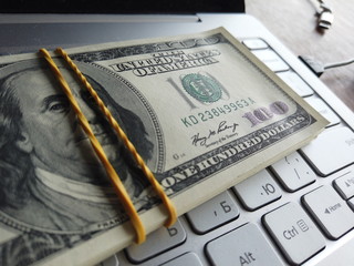 Stack of american dollars on laptop keyboard background. A lot of american dollars on the keyboard...