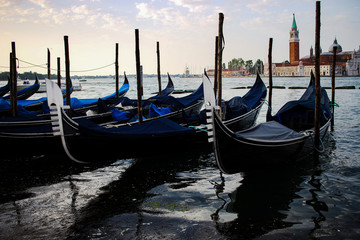 Fototapeta na wymiar A row of gondolas lined up by the dock in Venice, Italy