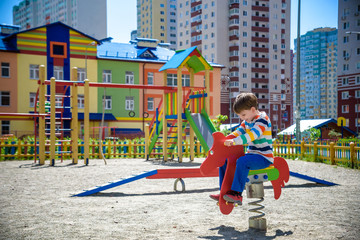 Fototapeta na wymiar Cute little boy having fun on outdoor playground. Spring/summer/autumn active sport leisure for kids. Outdoors wooden equipment for children game