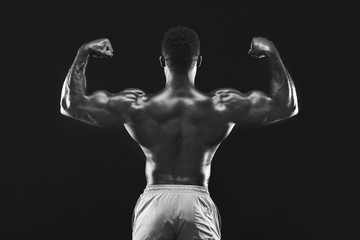 Black and white photo of strong muscular athlete flexing muscles