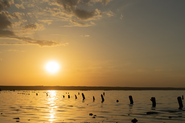 Sunset on the Kuyalnik Liman. Odessa. Ukraine. Old logs are visible from the water - the remains of an ancient pier.