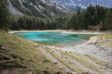 Naklejka na ściany i meble Turquoise lake in Austria. Bench is near the quiet lake. 