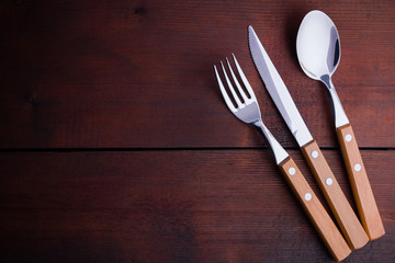 Rustic set of cutlery knife, spoon, fork. Dining set with wooden handles. Wooden background. Copy space. Top view