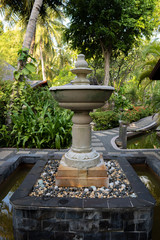 Fountain in a tropical park with a small pond. © Raman