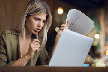 YBusinesswoman reading documents while working in a cafe
