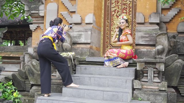 Female photographer taking picture of balinese dancer with traditional costume in the temple. Shot in 4k resolution