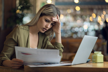 Displeased businesswoman reading problematic reports in a cafe