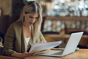 Businesswoman reading documents while working in a cafe
