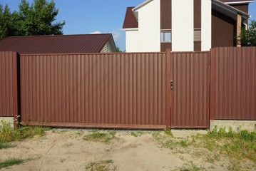Fototapeta premium long private closed metal gate of brown color on the street