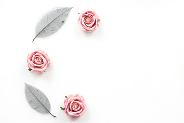 Pink rose flowers and black leaves on white background, flat lay, top view