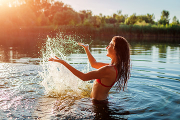 Young woman in bikini playing in water and making splash. Summer vacation