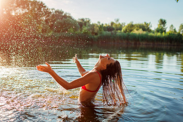 Young woman in bikini playing in water and making splash. Summer vacation
